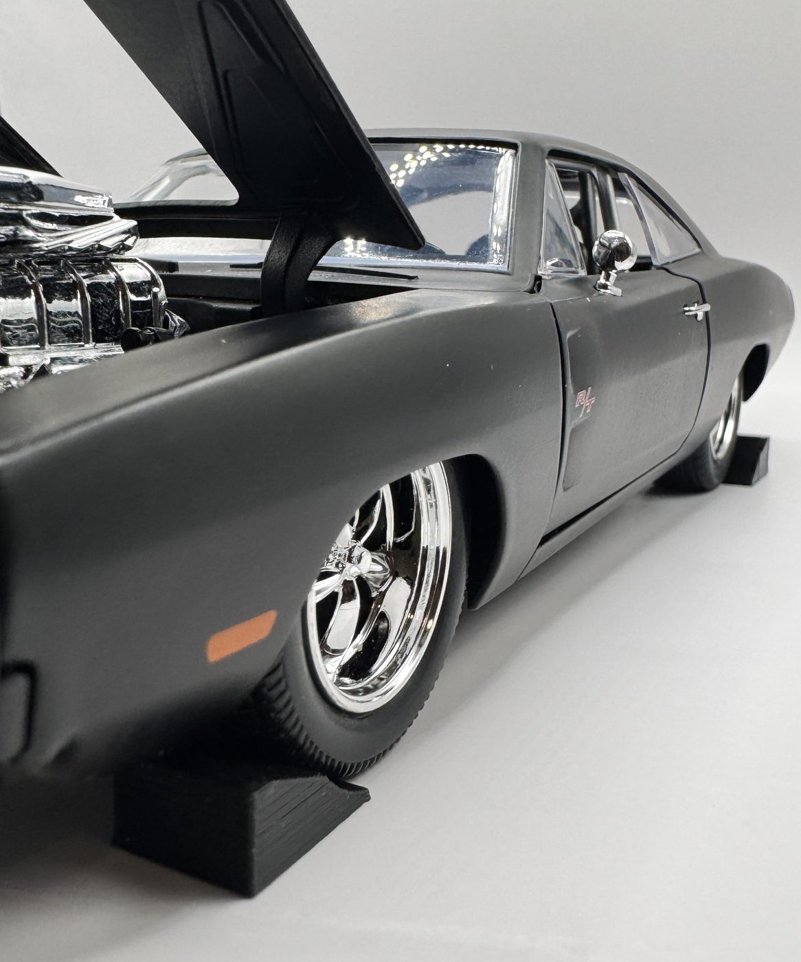Black 1:24 scale wheel chock in front of the tire of a 1:24 diecast muscle car